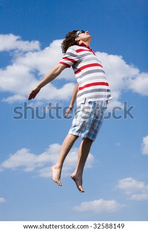Portrait of energetic man in high jump against bright blue sky
