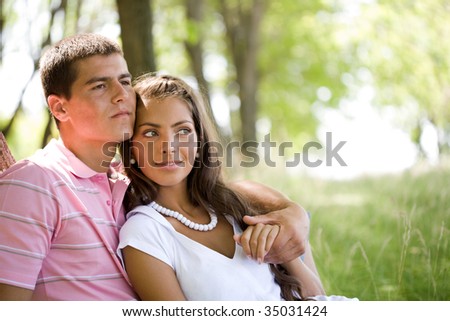 Image of amorous couple holding each other by hands while relaxing outside
