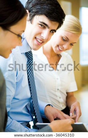 Smart leader looking at camera surrounded by his co-workers