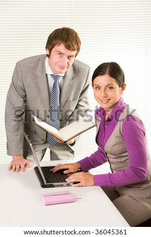 Photo of happy co-workers looking at camera during teamwork in office