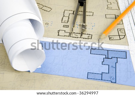 Close-up of blueprints with sketches of projects on workplace and some mechanical tools