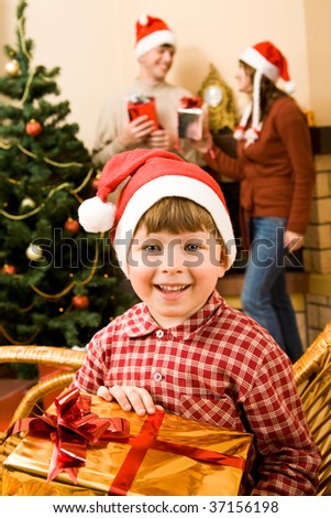 Happy lad with gift in hands looking at camera with smile on Christmas day