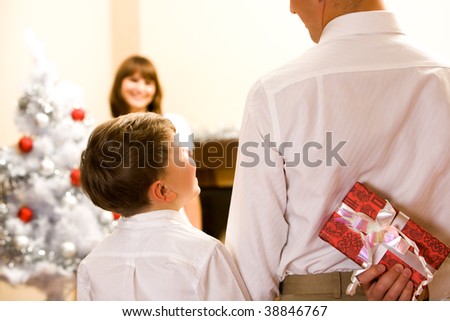 Rear view of man holding giftbox in hand with his son near by