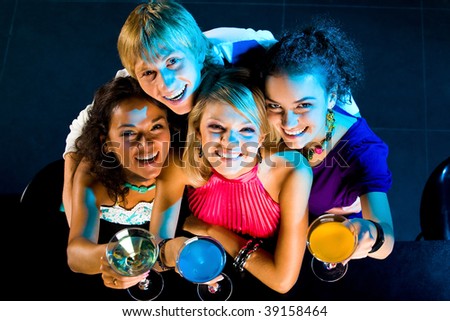 Above angle of happy friends cheering up while handsome guy embracing girls