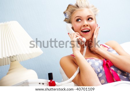 Portrait of surprised female in curlers speaking on the telephone at home