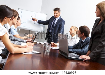 Image of smart business people looking at their leader while he explaining something on whiteboard during seminar