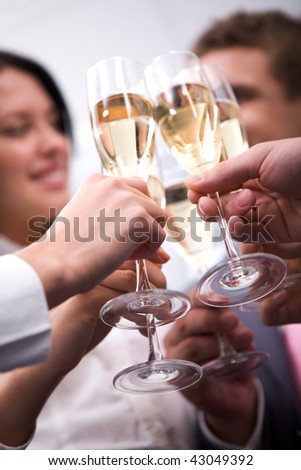 Close-up of human hands cheering up with flutes of golden champagne