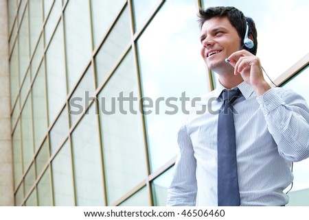 Photo of handsome guy speaking on the headset outdoors