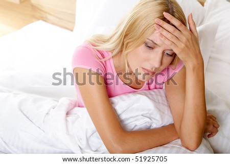 Above view of ill woman in bed touching her head