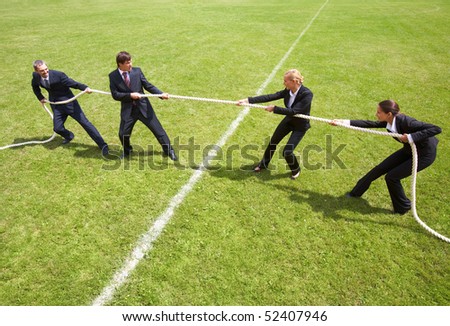 Businessmen and businesswomen playing tug of war