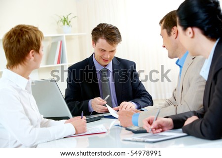 Portrait of confident manager looking at document and giving consulting to business people