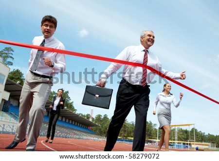 Photo of happy mature businessman crossing finish line during race