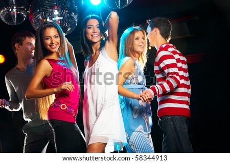 Joyful Girls Dancing In Night Club With Their Friends Near By Stock ...
