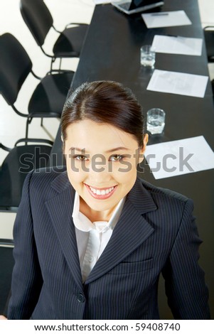 Portrait of pretty woman looking at camera with smile on the background of long table and chairs