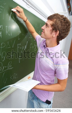 Portrait of smart lad by the blackboard writing formulae