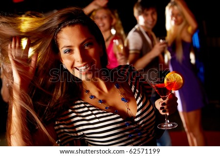 Portrait of cheerful girl dancing at party while smiling at camera