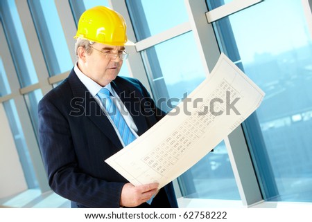 Portrait of mature foreman holding a project and looking at it