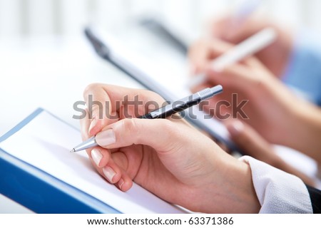 Image of human hand writing on paper at seminar or conference