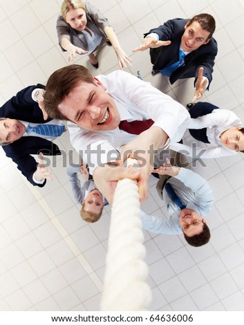 Above view of happy employer ascending up the rope with several employees beneath