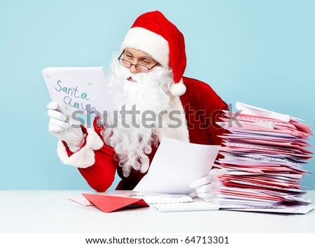 Image of Santa Claus in front of heap of letters reading one of them