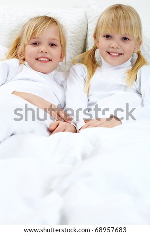 Portrait of two adorable sisters lying in the bed