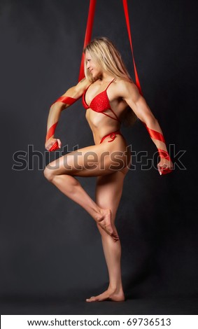 A beautiful model in red bikini marching to the left with red ribbons wound round her arms