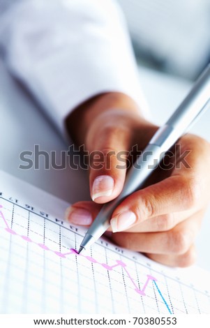 Close-up of business person hand with pen over paper