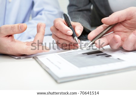 Image of several hands over business charts