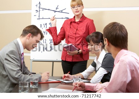 Photo of smart woman pointing at whiteboard at seminar while business partners listening to her