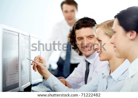 Businesswoman pointing at computer monitor showing it to her colleagues