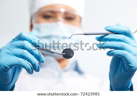Image of assistant in medical uniform holding dentistry tools in hands