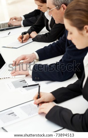 Image of row of people writing on papers and typing at briefing
