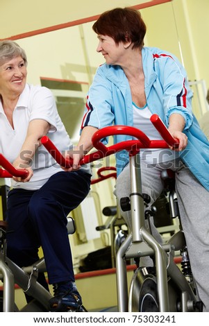 Portrait of senior females doing physical exercise on special equipment in gym