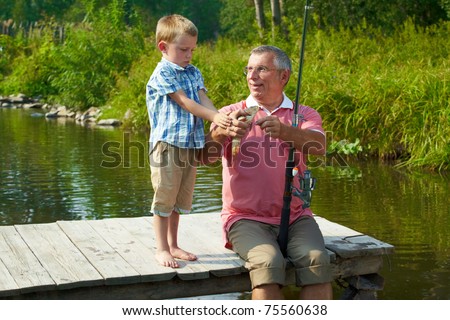 Photo of grandson looking at fish caught by his grandfather