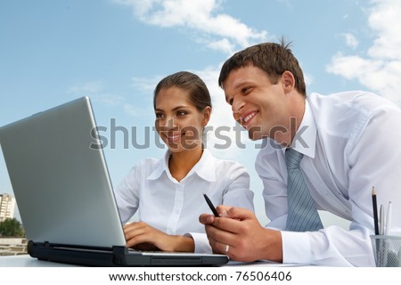 Portrait of friendly people looking at laptop monitor while working at new project