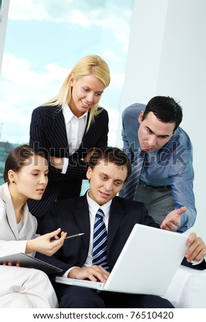 Portrait of several colleagues looking at laptop screen in office