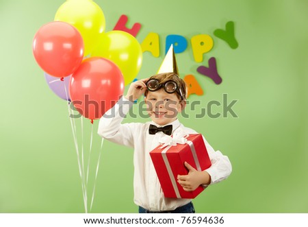 Portrait of happy lad with giftbox putting off funny eyeglasses on birthday party
