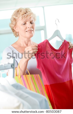 Portrait of middle aged woman choosing new tanktop in clothing department