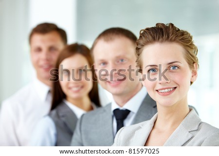 Portrait of friendly leader looking at camera with three employees behind