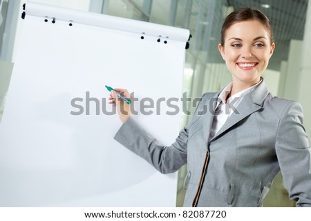Image of young woman pointing at whiteboard at meeting