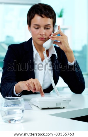 Photo of smart businesswoman dialing phone number in office