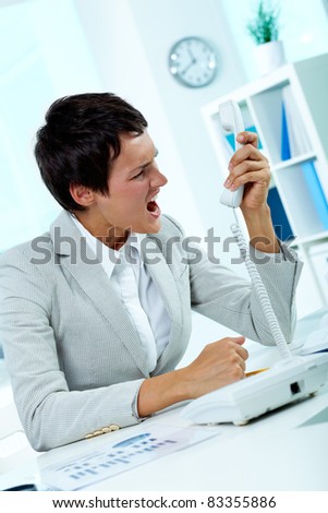 Image of annoyed boss losing her temper and screaming into phone receiver