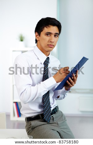 Portrait of a businessman writing plan of work in office