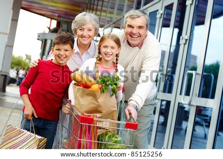 Portrait of happy grandparents and grandchildren near supermarket