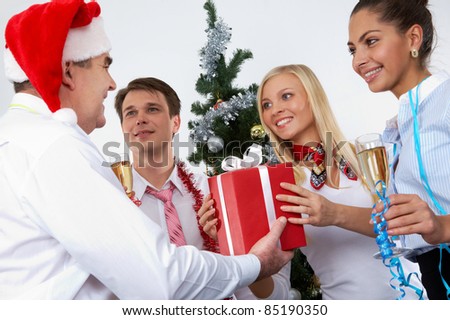Image of cheering associates taking gifts from ceo in Santa cap at corporate party