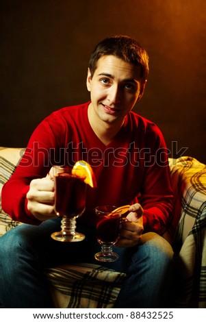 Portrait of young man with two glasses of tea offering one to you