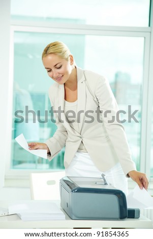 A beautiful businesswoman printing documents in office