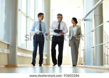 Confident business partners walking down in office building and discussing work
