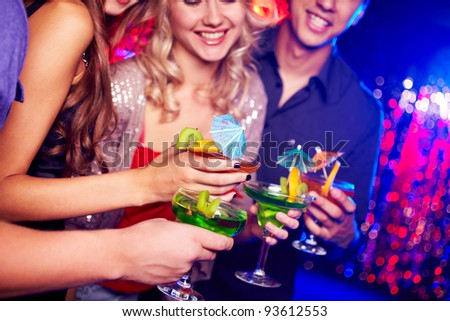 Close-up of several cocktails in hands of young people during party