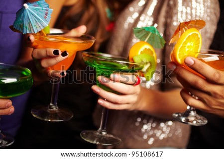 Young people holding cocktails at a birthday party, their faces being offscreen